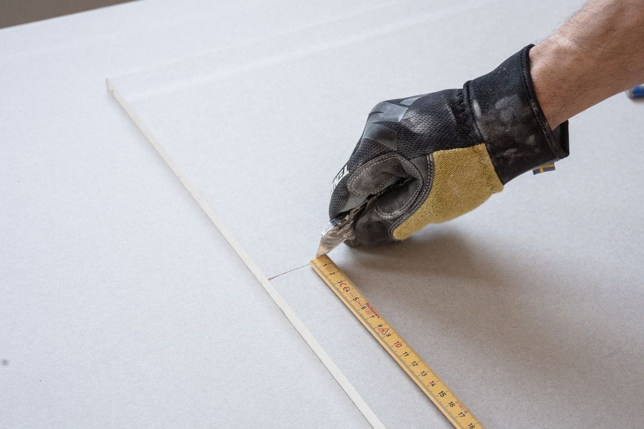 Home A gloved hand using a ruler for precise measurements in a construction project.