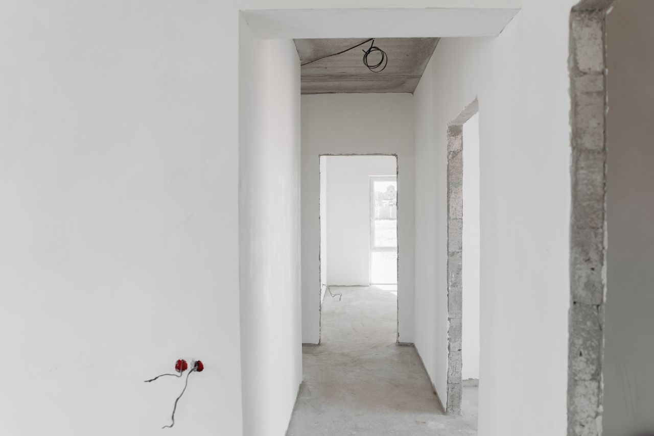 Home A minimalist view of an unfinished building interior with white walls and door frames.